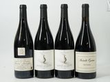four bottles of wine are lined up on a white surface