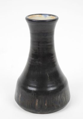 un vase noir posé sur une surface blanche