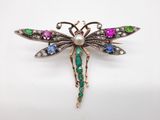 un gros plan d'une broche en forme de libellule ornée de pierres multicolores
