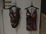 two women ' s swimsuits hanging on a rack in a bathroom