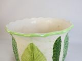a green and white planter with leaves on it
