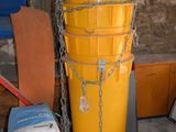 un grand seau jaune posé à côté d'une pile de cartons