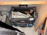 un sac noir rempli d'objets posé sous un bureau
