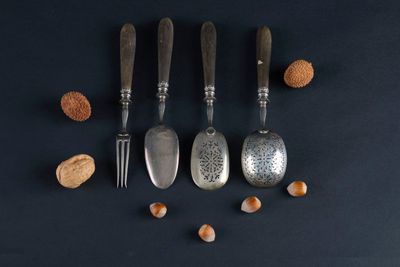 four spoons and two forks with nuts on a black surface
