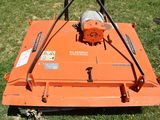 an orange lawn mower sitting on top of a lush green field