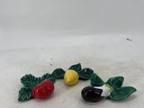 two small figurines of fruits and leaves on a white surface
