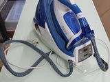 un fer à repasser à vapeur bleu et blanc posé sur une table blanche