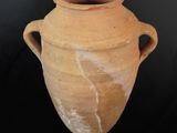 un grand vase en argile muni d'anses, sur fond noir