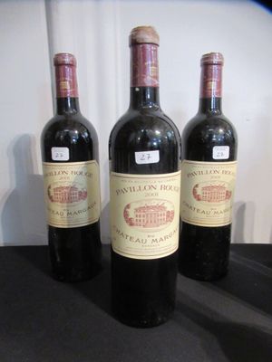 Trois bouteilles de vin sont alignées sur une table noire