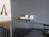 a small kitchen with a table and a shelf with utensils on it