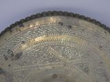 a silver plate with a design on it on a table