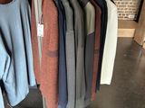 clothes hanging on a rack in a clothing store next to a brick wall