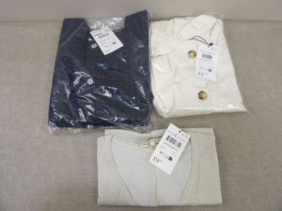trois chemises pour homme posées sur un canapé, avec leurs étiquettes encore attachées