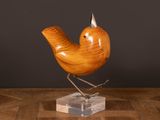 un oiseau en bois posé sur un socle transparent