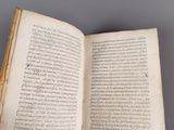 an open book with a hand holding it in it ' s left hand
