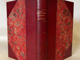 un vieux livre à la couverture rouge posé sur une table blanche