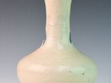 a green vase sitting on a white surface