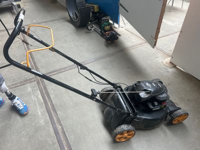 un petit garçon qui joue avec une tondeuse à gazon