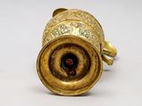 a gold vase with a red stone inside of it