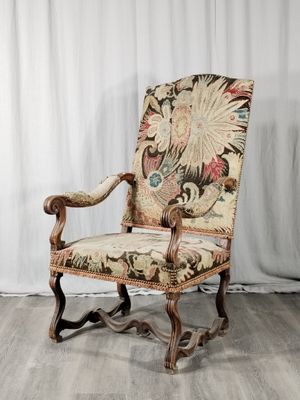 une vieille chaise avec un dossier et des accoudoirs tapissés de fleurs