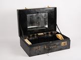 une valise noire contenant un miroir, posée sur une surface blanche