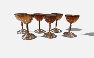 six wine glasses are lined up in a row on a white surface