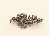 an image of a silver broochle with flowers and leaves