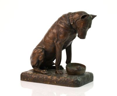 statue en bronze représentant un chien avec un bol de nourriture posé sur une surface blanche