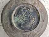 a metal bowl with a fish on it on a table