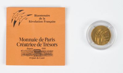 une pièce d'or posée à côté d'un livret sur une surface blanche