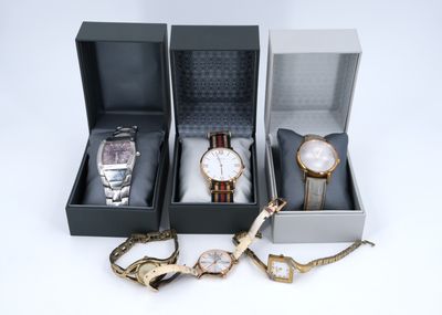 trois montres et un bracelet dans un coffret posé sur une surface blanche