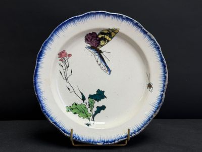 une assiette bleue et blanche décorée d'un papillon et de fleurs