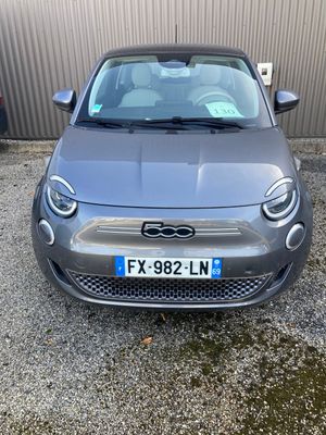 a grey car parked in front of a building next to a parking lot
