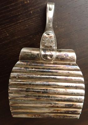 un porte-monnaie plaqué argent posé sur une table en bois, muni d'une poignée en métal