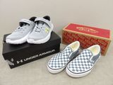 des chaussures Vans Slip-On à motif damier dans une boîte, à côté d'une autre boîte contenant une paire de chaussures