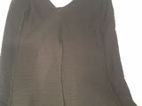 the back of a black dress hanging on a hanger on a white wall