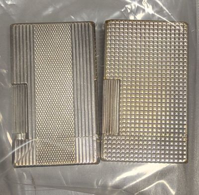 two silver cigarette cases sitting on top of a plastic bag
