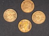 quatre types différents de pièces d'or sur une surface noire