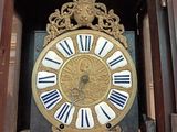 a clock that is in a wooden case with roman numerals on it