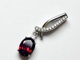 Gros plan sur un pendentif en pierre rouge et diamants posé sur une surface blanche