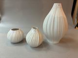 three white vases sitting on a table next to each other