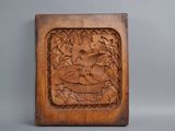 wooden carving of a bird in a tree surrounded by leaves