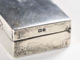 a silver cigarette case sitting on a white surface