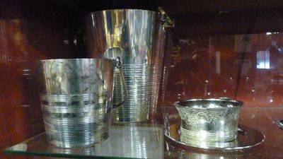 une étagère en verre sur laquelle sont posées des tasses en argent, dont une