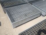Plusieurs grilles en acier sont empilées les unes sur les autres au sol