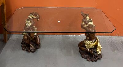 une table en verre sur laquelle trône une statue en bronze