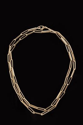 a close up of a gold necklace on a black background