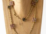 a close up of a necklace on a mannequin on a wooden surface