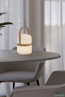 une table sur laquelle se trouve une lampe, avec une chaise placée devant une fenêtre