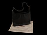 the black purse is sitting on top of a white bag